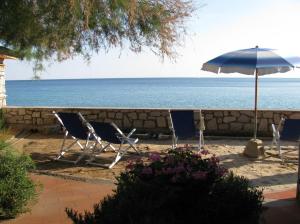 twee stoelen en een paraplu naast de oceaan bij Onda Su Onda Appartamenti in Seccheto