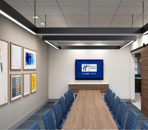 a conference room with a tv and blue chairs at Holiday Inn Express Cape Canaveral by IHG in Cape Canaveral +62 photos