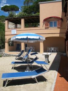 a group of chairs and an umbrella in front of a building at Onda Su Onda Appartamenti in Seccheto