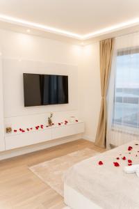 Sala de estar blanca con TV y rosas rojas en la cama en SINFONIA LUX en Belgrado