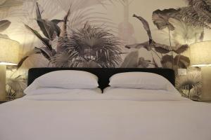 a bed with white pillows and a wall with plants at Trevi Fountain Luxury Flat in Rome