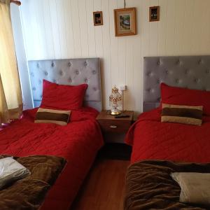 a bedroom with two beds with red sheets and a headboard at Casa dos dormitorios in Iquique