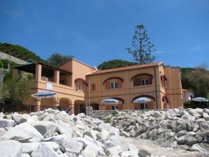 a building with a bunch of rocks in front of it at Onda Su Onda Appartamenti in Seccheto