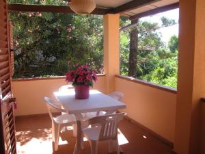 a table and chairs in a room with two windows at Onda Su Onda Appartamenti in Seccheto