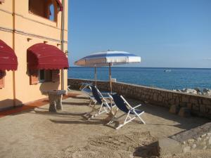 two chairs and an umbrella next to the ocean at Onda Su Onda Appartamenti in Seccheto