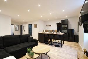 un soggiorno con divano nero e una cucina di Le Contemporain*WIFI*Central a Saint-Laurent-sur-Saône