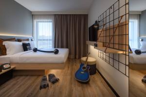 Un dormitorio con una cama con una guitarra. en Moxy Lisboa Oriente en Lisboa