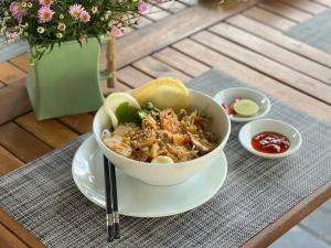 a bowl of food on a plate on a table at Mayci Boutique Hotel Hoi An in Hoi An