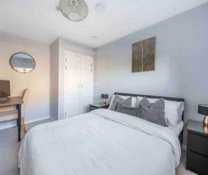 3 Bedroom Penthouse Apartment Central Maidenhead في ميدينهيد: غرفة نوم مع سرير أبيض كبير ومكتب
