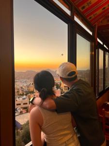 een man en vrouw die uit een raam kijken bij de zonsondergang bij Petra Wooden House in Wadi Musa