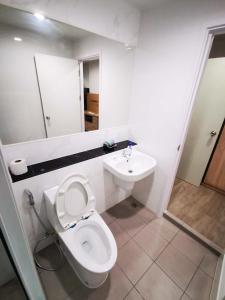 a white bathroom with a toilet and a sink at Bangkok Sathon RYE condo in Bangkok