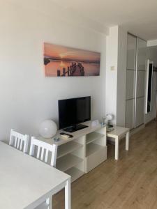 sala de estar con TV, mesa y sillas en Apartamentos Chinasolymar, en Almuñécar