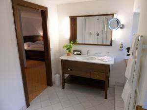 un bagno con lavandino, specchio e letto di Hotel Gasthof Der Jägerwirt a Bergheim