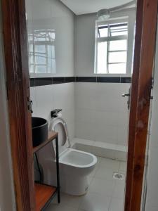 La salle de bains blanche est pourvue de toilettes et d'une fenêtre. dans l'établissement Sandalwood Suites Nakuru - Studios & One Bedroom Suites, à Nakuru