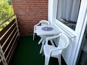 a white table and chairs on a balcony with a window at Bright & Cozy Apartment in Plettenberg