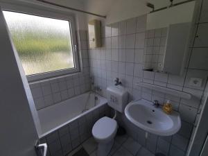 uma casa de banho com um lavatório, um WC e uma janela. em Bright & Cozy Apartment em Plettenberg