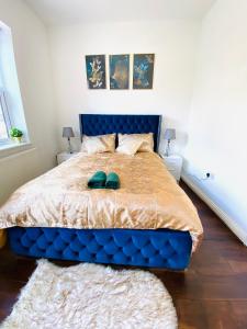 a bedroom with a blue bed with two green shoes on it at Luxury Morden 4 bedroom Flats which will make you unforgettable in London