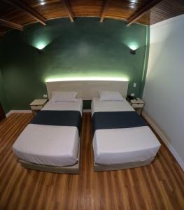 two beds in a room with green walls and wooden floors at Hotel El Arroyo in Caracas