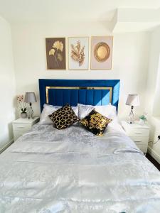 Luxury Morden 4 bedroom Flats which will make you unforgettable في لندن: سرير مع اللوح الأمامي الأزرق والوسائد عليه