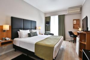 サンパウロにあるFlat Privativo Comfort Ibirapueraの大型ベッドとテレビが備わるホテルルームです。