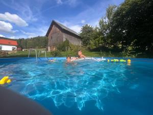 2 bambini nuotano in una piscina di Chalupa U Franze a Malá Morava