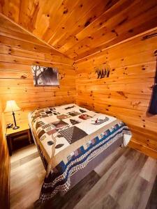 een slaapkamer met een bed in een houten hut bij Willow Cabin in Thompsonville