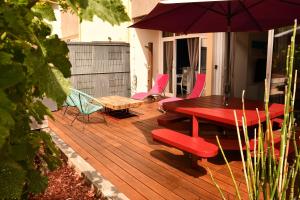 une terrasse en bois avec une table, des chaises et un parasol dans l'établissement kerloch gwen, à Combrit