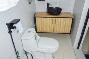 La salle de bains est pourvue de toilettes blanches et d'un lavabo. dans l'établissement Sandalwood Suites Nakuru - Studios & One Bedroom Suites, à Nakuru