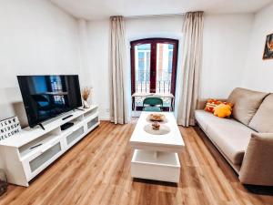 Una sala de estar con un sofá y un televisor. en Apartamento TIENDAS 8, en Almería