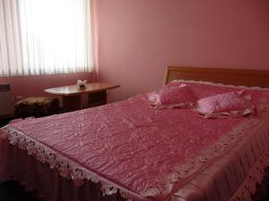 a bedroom with a pink bed with a pink comforter at Skaistažiedė in Šiauliai