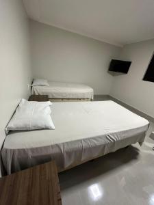 a bedroom with two beds and a table at Nasser Hotel Aeroporto in Núcleo Bandeirante