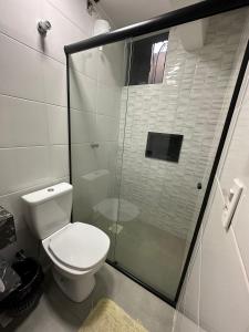 uma casa de banho com um WC e uma cabina de duche em vidro. em Nasser Hotel Aeroporto em Núcleo Bandeirante