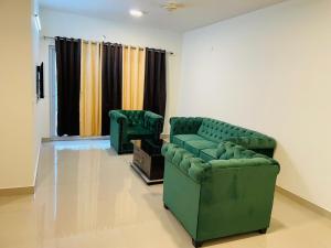 a living room with two green chairs and curtains at ACHYUTAM HOMES in Lucknow