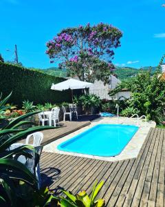 a pool with chairs and an umbrella on a wooden deck at Casa da Rosa hospedagem em Florianópolis in Florianópolis