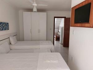 Un dormitorio con dos camas y un televisor de pantalla plana. en Casa 22B, MONT HEBROM, en Porto Seguro