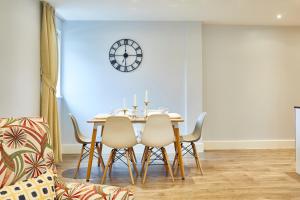 a dining room table with chairs and a clock on the wall at Elegant Plus Luxury Apartments in London