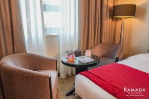 a hotel room with a bed and two chairs and a table at Ramada Downtown Abu Dhabi in Abu Dhabi