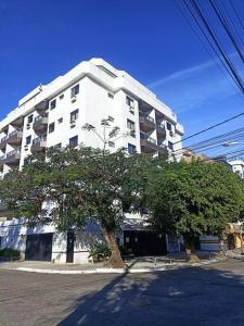 a large white building with a tree in front of it at Cabo Frio apartamento Casa Mar in Cabo Frio