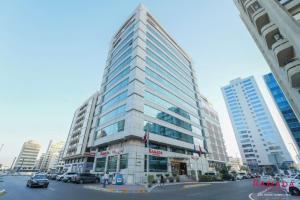 a tall building with cars parked in a city at Ramada Downtown Abu Dhabi in Abu Dhabi