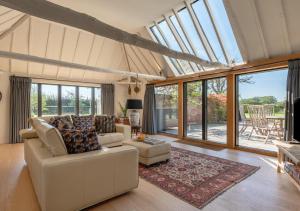 a living room with a couch and chairs and windows at Alexandra Barn in Shadingfield