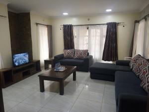 een woonkamer met 2 banken en een salontafel bij Serene Modern 3 bedroom house near Mombasa Road in Emali