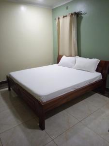 een bed in een kamer met witte lakens en kussens bij Serene Modern 3 bedroom house near Mombasa Road in Emali