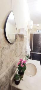 ein Badezimmer mit einem Waschbecken, einem Spiegel und Blumen in der Unterkunft Recanto das Neves in Miguel Pereira