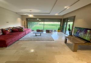 a living room with a red couch and a table at Condo à Prestigia Agate - Golf city Marrakech in Marrakech