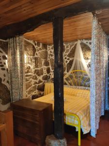 una cama en una habitación con una pared de piedra en Casa Na Montanha Da Neve, en Seia