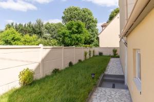 a backyard with a fence and a drain in the grass at calme appartement de vacances in Écouen