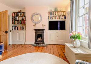 a living room with a fireplace and a mirror at Celebration Cottage - Southwold in Southwold