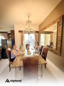 un grupo de personas sentadas alrededor de una mesa de comedor en Alphatel Beach Hostel JBR en Dubái