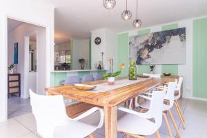 a dining room with a wooden table and white chairs at Haus at Chappies in Noordhoek
