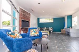 ein Wohnzimmer mit 2 blauen Stühlen und einem Tisch in der Unterkunft Haus at Chappies in Noordhoek